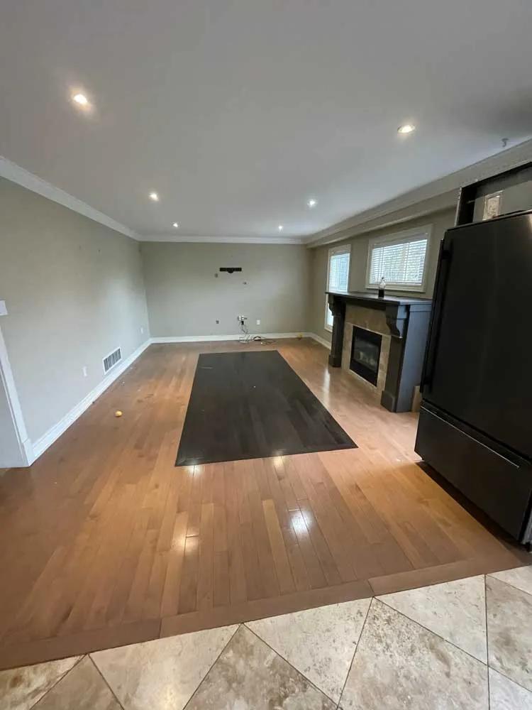 Large living room with hardwood flooring and an area rug before removal